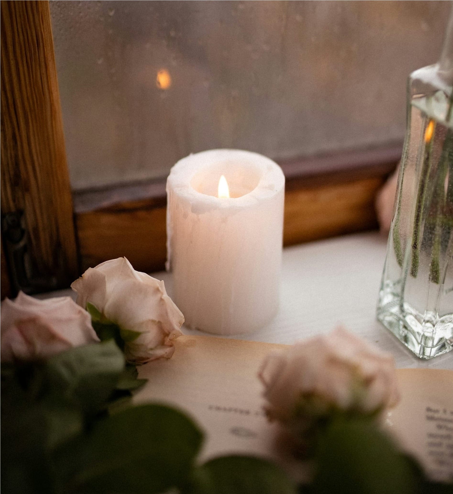 a candle and some flowers on a window sill